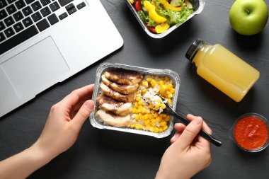 Gri masadaki yemek kutusundan yemek yiyen kadın, yakın plan. Sağlıklı yemek servisi.