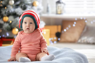 İçeride battaniyeye elf şapkası takan küçük bir bebek. İlk Noel