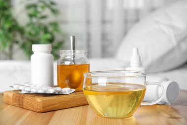 Limonlu bir bardak sıcak çay ve ahşap masada farklı soğuk çareler.