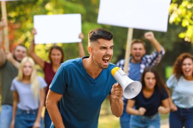 Dışarıda megafonla protesto yapan öfkeli genç bir adam.