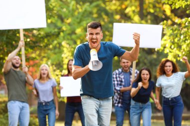 Dışarıda megafonla protesto yapan öfkeli genç bir adam.
