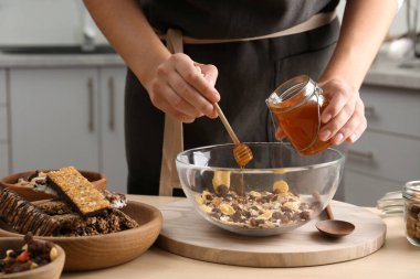 Mutfaktaki ahşap masada sağlıklı granola barı hazırlayan kadın.