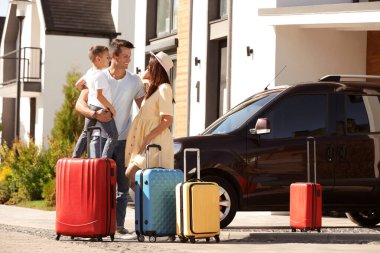 Happy family with suitcases near house outdoors. Moving day clipart