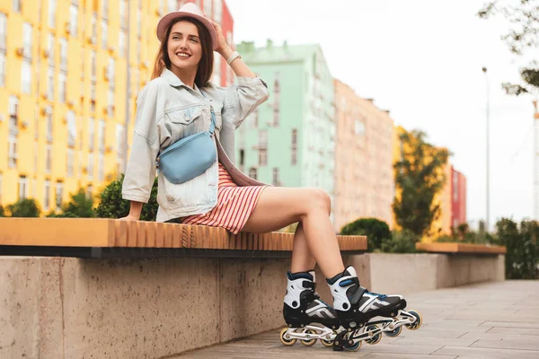Hermosa mujer joven con patines de ruedas sentado en el banco al aire libre —  Fotos de Stock