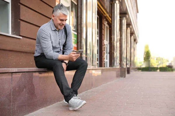 Retrato de hombre de negocios guapo con teléfono móvil en la ciudad — Foto de Stock
