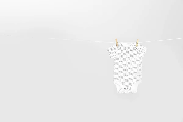 Lindo bebé onesie colgando en la línea de ropa contra el fondo gris claro, espacio para el texto. Día de lavandería — Foto de Stock