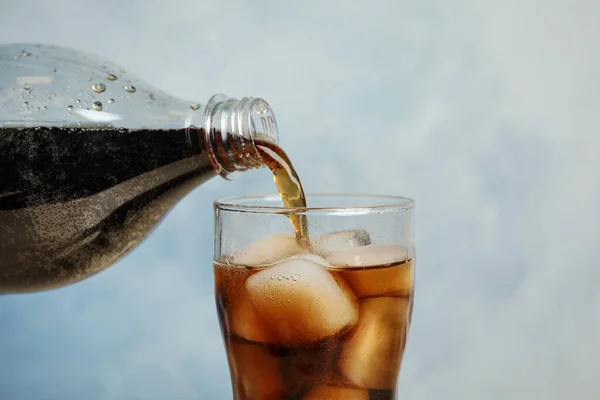 Verter refrescante bebida de soda en el vaso sobre fondo azul, primer plano — Foto de Stock
