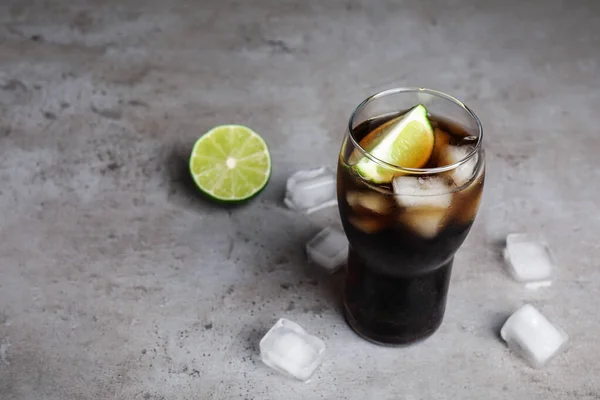 Bebida refrescante de refrigerante, cubos de gelo e limão na mesa cinza, espaço para texto — Fotografia de Stock