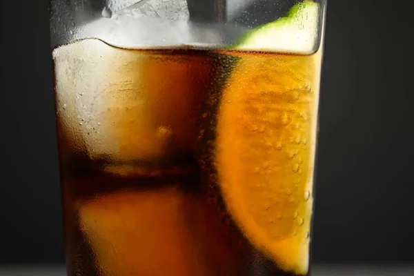 Glass of refreshing soda drink with lime and ice cubes on grey background, closeup — Stock Photo, Image