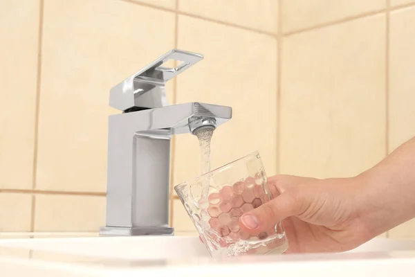 Woman filling glass with water from faucet indoors, closeup — Stock Photo, Image