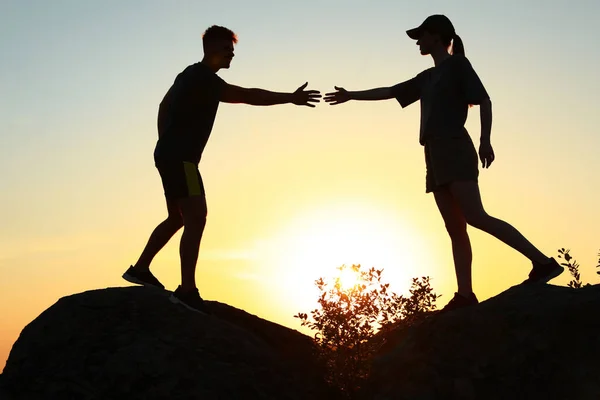 Wandelaar helpt vriend buitenshuis bij zonsondergang. Help en ondersteuning concept — Stockfoto