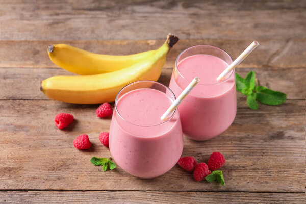 Glasses of tasty raspberry banana smoothie on wooden table