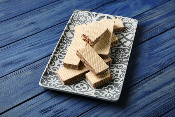 Assiette de délicieuses gaufrettes croustillantes avec garniture au chocolat sur table en bois bleue — Photo