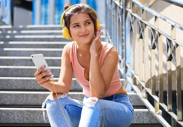 Junge Frau mit Kopfhörern hört Musik auf der Treppe — Stockfoto