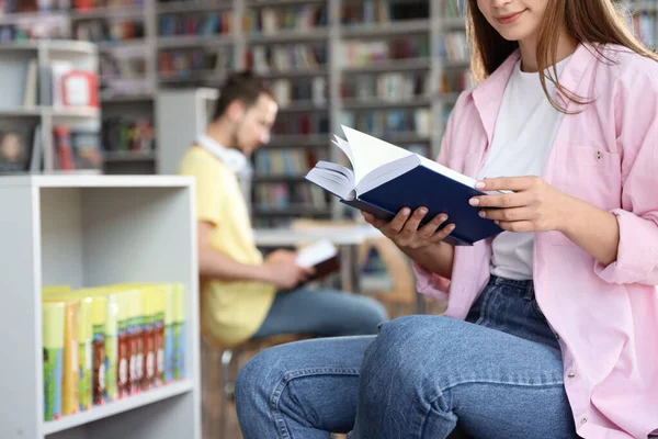 Jovem com livro na biblioteca, close-up — Fotografia de Stock