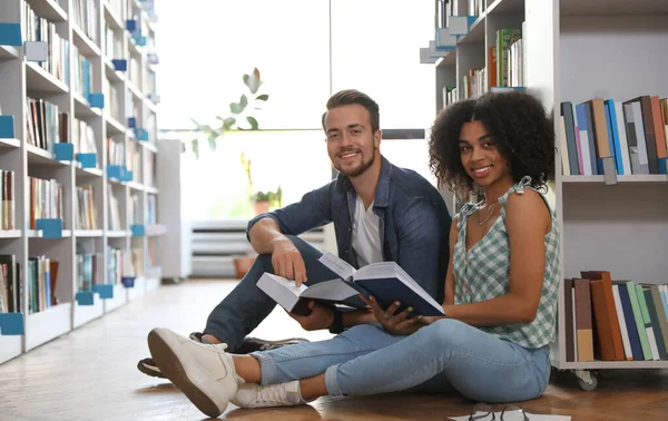 Young people with books on floor in library