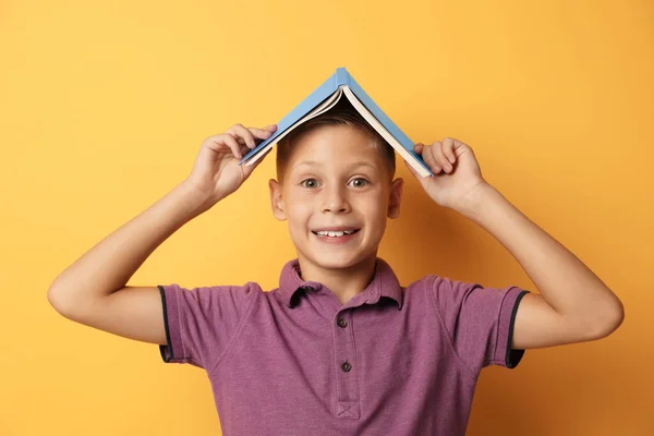 Retrato de niño lindo con libro sobre fondo amarillo. Concepto de lectura — Foto de Stock