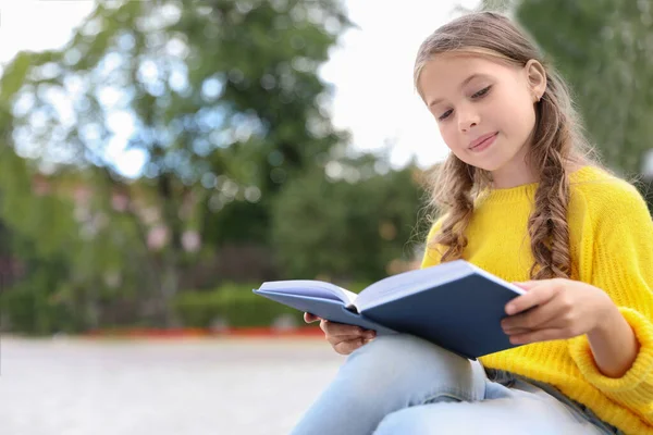 Cute Little Girl czytanie książki w zielonym parku — Zdjęcie stockowe