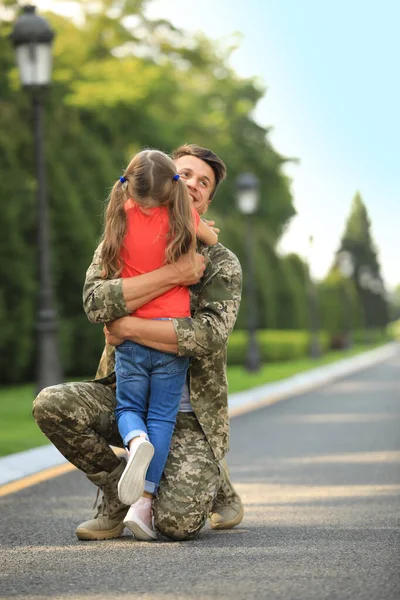 Πατέρας με στρατιωτική στολή αγκαλιάζει την κόρη του στο ηλιόλουστο πάρκο. — Φωτογραφία Αρχείου
