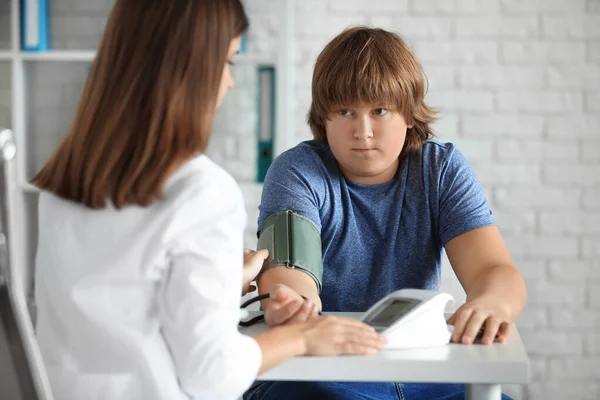 診療所で太りすぎの男の子の血圧をチェック女性医師 — ストック写真