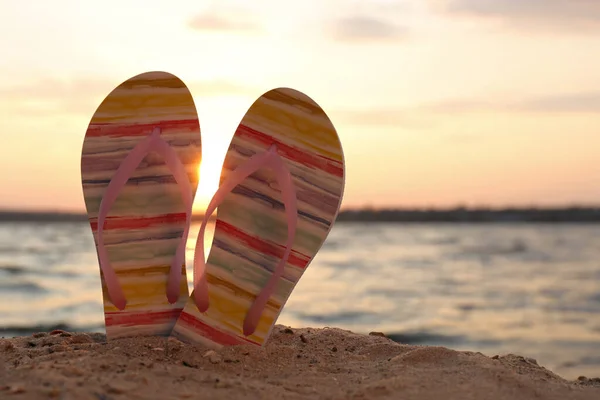 Stylish flip flops on sand near sea, space for text. Beach accessories — Stock Photo, Image