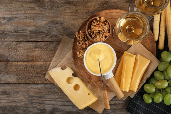 Composição de colocação plana com pote de fondue de queijo saboroso e produtos na mesa de madeira, espaço para texto — Fotografia de Stock