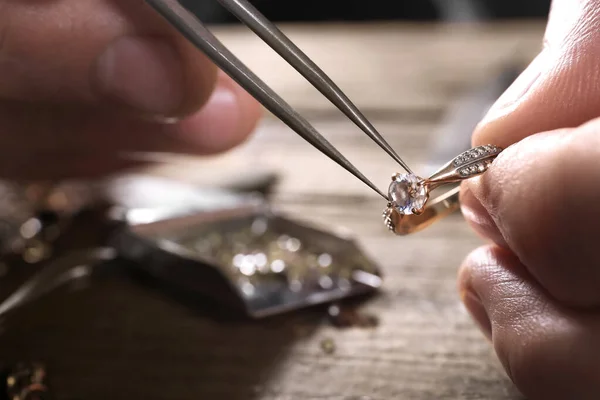 Male jeweler examining diamond ring in workshop, closeup view