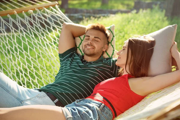 Junges Paar ruht sich in bequemer Hängematte im grünen Garten aus — Stockfoto