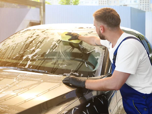 Young worker cleaning automobile with sponge at car wash — Stock Photo, Image