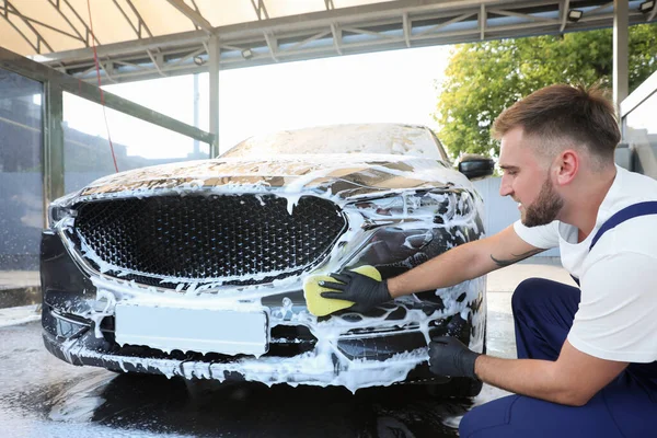 Joven trabajador de limpieza de automóviles con esponja en el lavado de coches — Foto de Stock