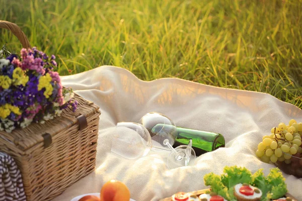 Dek met picknickmand en wijn op groen gras — Stockfoto