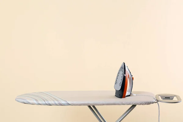 Tavola con ferro moderno su sfondo beige, spazio per testo. Giorno di lavanderia — Foto Stock