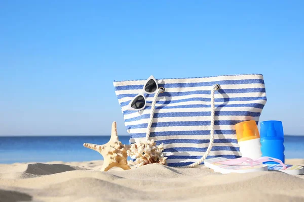 Conjunto com acessórios de praia elegantes na areia perto do mar — Fotografia de Stock