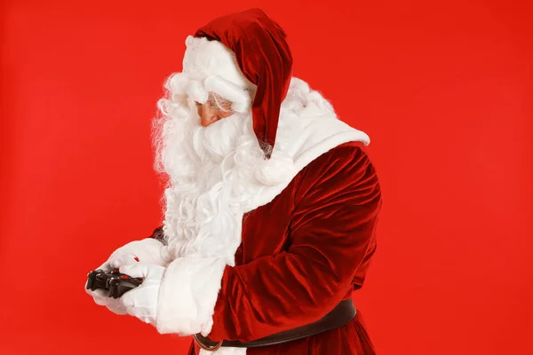 Autêntico Papai Noel com controlador de jogo em fundo vermelho — Fotografia de Stock