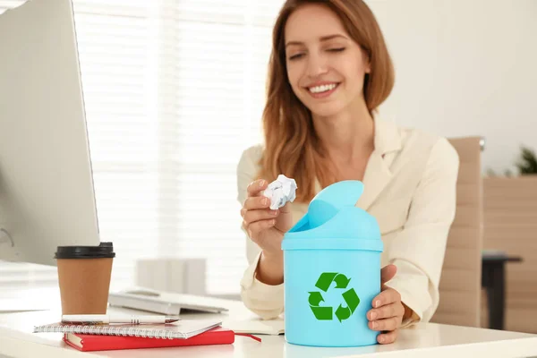Mujer joven arrojando papel en la mini papelera de reciclaje en la oficina —  Fotos de Stock
