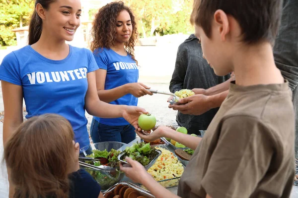 Volunteers serving food to poor people outdoors — Stock Photo, Image