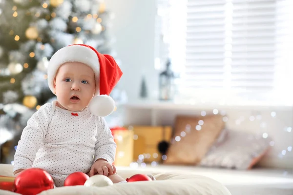 Małe dziecko w kapeluszu Mikołaja bawiące się kulkami świątecznymi wewnątrz — Zdjęcie stockowe