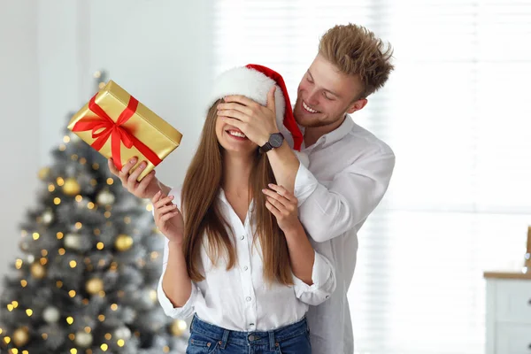 Genç adam kız arkadaşına evde Noel hediye vermek — Stok fotoğraf