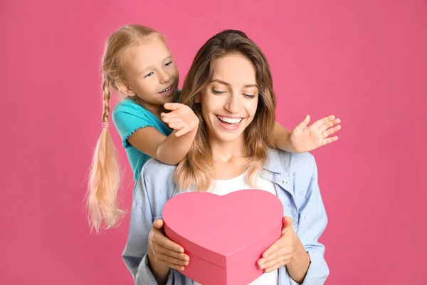 A kislány gratulál az anyjának a rózsaszín hátteréhez. Boldog anyák napját! — Stock Fotó