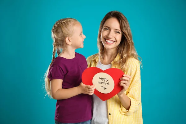 Little daughter congratulating her mom with card on blue background. Happy Mother's Day — Stok fotoğraf