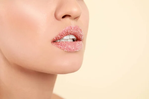Young woman with sugar scrub on lips against beige background, closeup — ストック写真