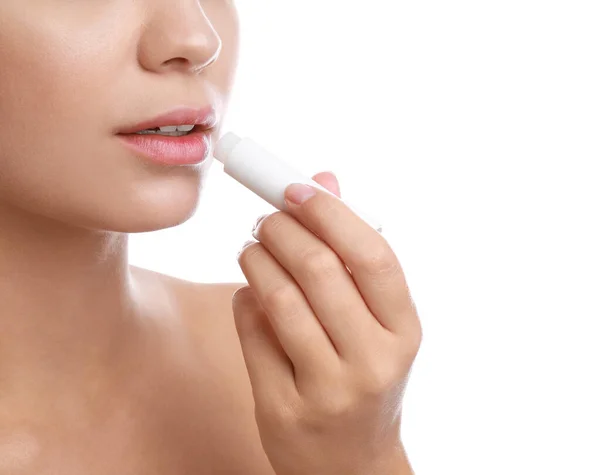 Jovem com ferida fria aplicando bálsamo labial contra fundo branco, close-up — Fotografia de Stock