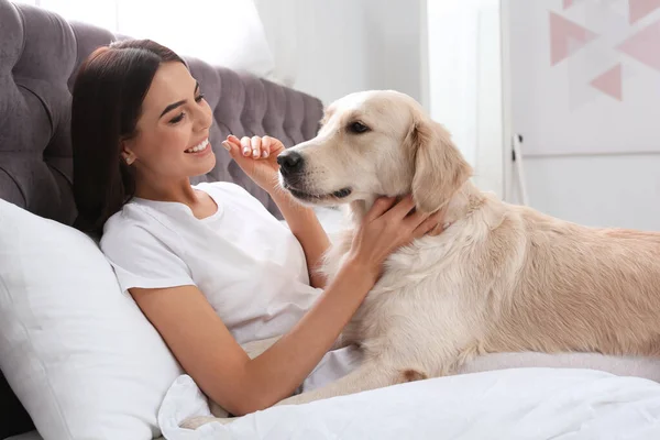 Ung kvinna och hennes Golden Retriever hund på sängen hemma — Stockfoto