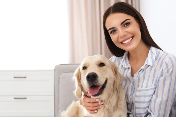 Jonge vrouw en haar Golden Retriever hond in de woonkamer. Ruimte voor tekst — Stockfoto