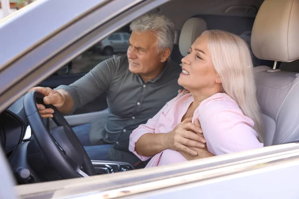 Senior homme tenant volant tandis que sa femme ayant une crise cardiaque dans la voiture — Photo