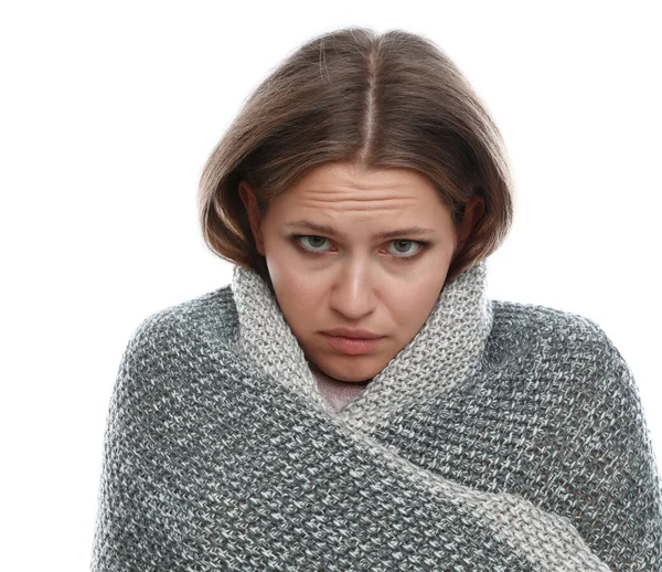 Молода жінка, загорнута в теплу ковдру, страждає від холоду на білому тлі — стокове фото