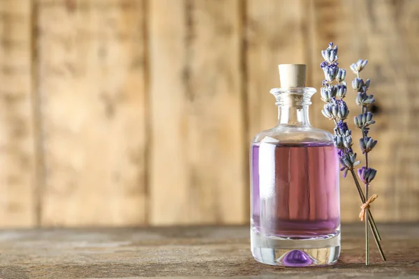 Flasche natürlichen ätherischen Öls und Lavendelblüten auf Holzgrund. Raum für Text — Stockfoto