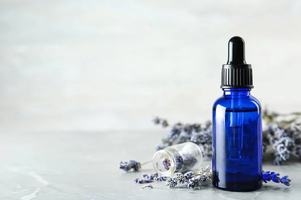 Flasche natürlichen ätherischen Öls und Lavendelblüten auf grauem Marmorhintergrund. Raum für Text — Stockfoto