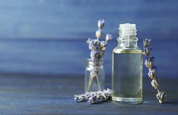 Botella de aceite esencial natural y flores de lavanda sobre fondo de madera azul. Espacio para texto — Foto de Stock
