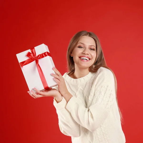 Joyeux jeune femme avec cadeau de Noël sur fond rouge — Photo